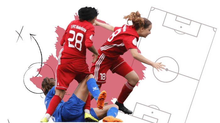 Zwei Fu&szlig;ballspielerinnen in roten Trikots jubeln, w&auml;hrend eine Spielerin auf dem Boden liegt, mit einem Fu&szlig;ballfeld im Hintergrund.