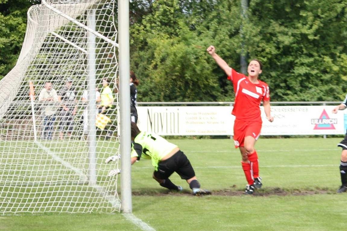 Fussballspiel: Torwart kniet vor dem Tor, während Spieler in rotem Trikot jubelt.