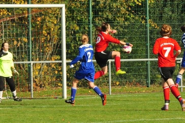 Spielszene mit einer Spielerin in rotem Trikot, die einen Ball im Flug hält, während andere Spielerinnen beobachten.