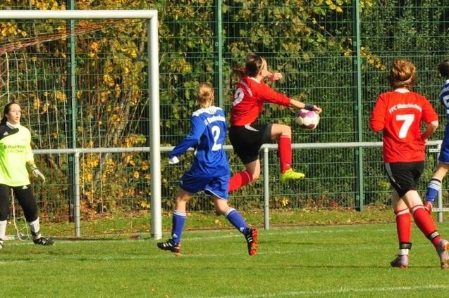 Spielszene mit einer Spielerin in rotem Trikot, die einen Ball im Flug h&auml;lt, w&auml;hrend andere Spielerinnen beobachten.