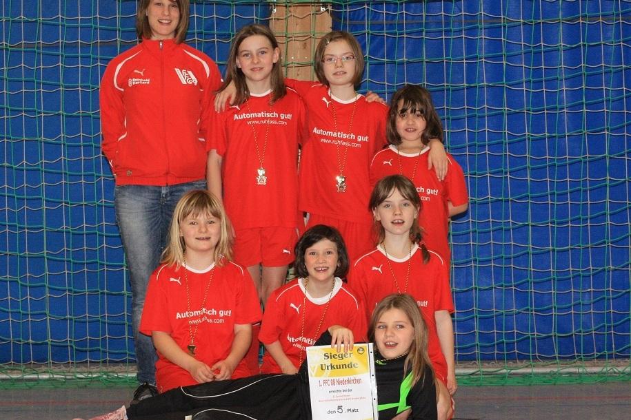 M&auml;dchenmannschaft in roten Trikots posaunt stolz mit Siegerurkunde vor einem Handballtor.