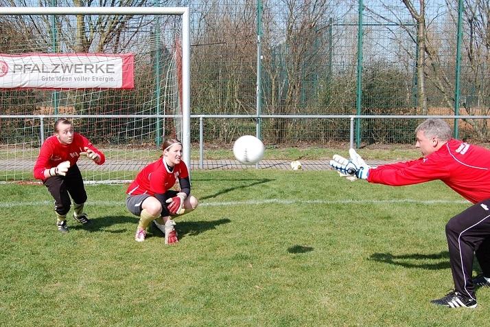 Zwei Torh&uuml;terinnen &uuml;ben im Trainingsspiel, w&auml;hrend ein Trainer einen Ball in ihre Richtung wirft.