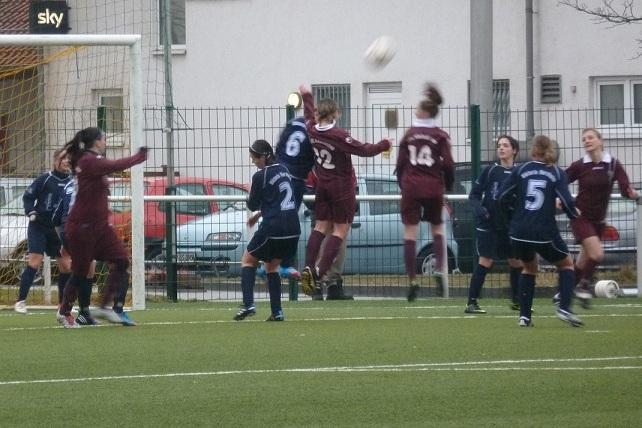 Frauenmannschaft beim Fu&szlig;ballspiel, zwei Spielerinnen springen, um einen hohen Ball w&auml;hrend einer Aktion zu erreichen.