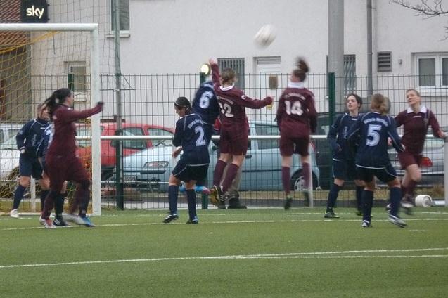 Frauenmannschaft beim Fu&szlig;ballspiel, zwei Spielerinnen springen, um einen hohen Ball w&auml;hrend einer Aktion zu erreichen.