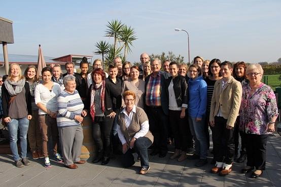 Gruppenfoto von 36 Personen im Freien, mit Palmen im Hintergrund an einem sonnigen Tag.
