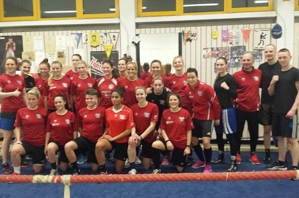 Gruppenfoto von 24 Frauen und einem Mann in roten Sportbekleidungen in einer Turnhalle.