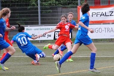 M&auml;dchenfu&szlig;ballspiel, eine Spielerin in roter Ausr&uuml;stung dribbelt den Ball, w&auml;hrend andere Spielerinnen versuchen, ihn zu erobern.