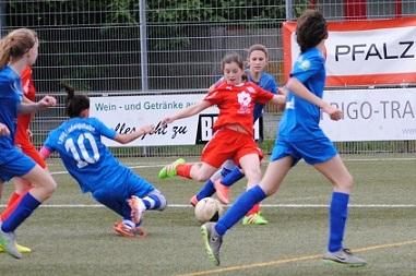 M&auml;dchenfu&szlig;ballspiel, eine Spielerin in roter Ausr&uuml;stung dribbelt den Ball, w&auml;hrend andere Spielerinnen versuchen, ihn zu erobern.