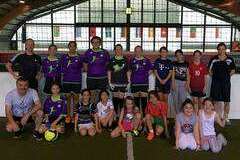 Gruppe von Fu&szlig;ballspielenden, bestehend aus Erwachsenen und Kindern, in einer Sporthalle.
