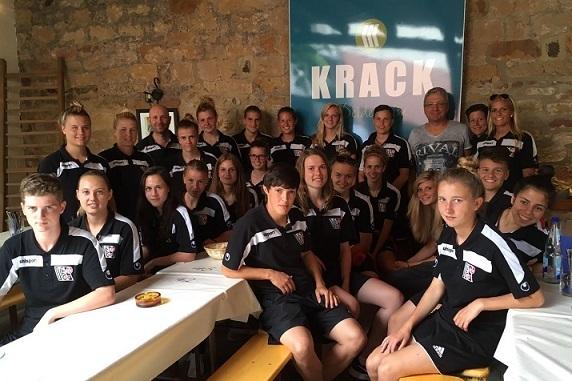 Gruppenfoto eines Sportteams in Schwarz-Wei&szlig;-Uniformen, sitzend in einem Raum mit Holzdecken und Wandtapete.