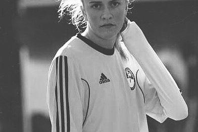 Portr&auml;t einer Fu&szlig;ballspielerin in Trainingskleidung, die nachdenklich in die Kamera schaut.