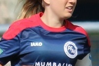 Eine Fu&szlig;ballspielerin in blauer Mannschaftsuniform sprintet auf dem Platz, mit einem entschlossenen Ausdruck im Gesicht.