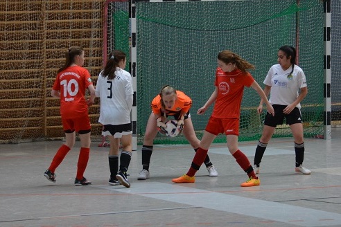 M&auml;dchenfu&szlig;ballspiel in einer Halle, Torh&uuml;terin f&auml;ngt den Ball, mehrere Spielerinnen von beiden Teams in der N&auml;he.