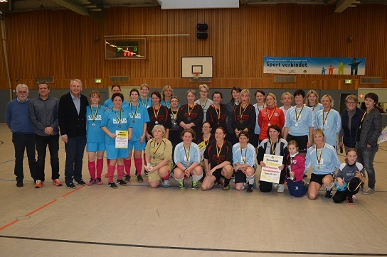 Gruppenfoto von Frauen mit Medaillen in Sportkleidung, die in einer Halle f&uuml;r ein Turnier posieren.