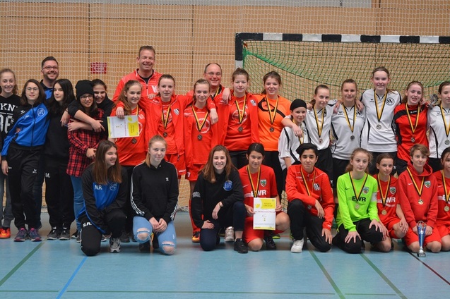 Gruppenfoto von M&auml;dchenmannschaften mit Medaillen und Platzierungsurkunden nach einem Handballturnier in der Sporthalle.