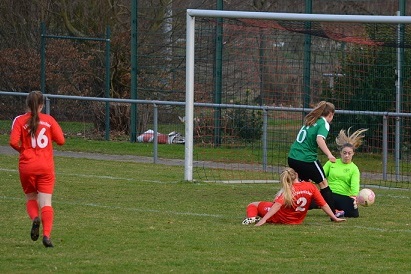 Zwei Fu&szlig;ballspielerinnen k&auml;mpfen um den Ball in der N&auml;he des Torwarts auf dem Spielfeld.
