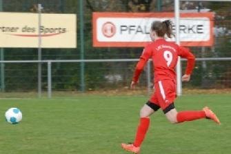 Spielerin in rotem Trikot mit der Nummer 9 läuft mit einem Fußball über das grüne Spielfeld.