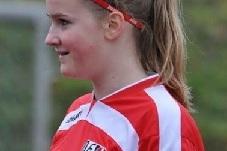 Profilansicht eines Mädchens in rotem Fußballtrikot mit Haarband und einem freundlichen Ausdruck.