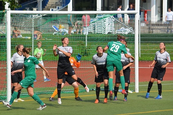 Spielszene im Frauenfu&szlig;ball: Spielerinnen in gr&uuml;nen und schwarzen Trikots in der N&auml;he des Torraums w&auml;hrend einer Aktion.