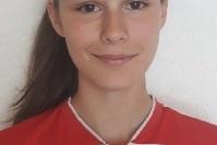 Portr&auml;t einer jungen Fu&szlig;ballspielerin in rotem Trikot mit Vereinslogo, vor hellem Hintergrund.