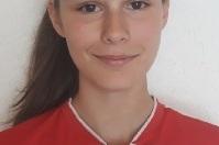 Portr&auml;t einer jungen Fu&szlig;ballspielerin in rotem Trikot mit Vereinslogo, vor hellem Hintergrund.