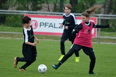Zwei Kinder im Fu&szlig;ballspiel, eines dribbelt den Ball, w&auml;hrend ein anderes zum Torschuss ansetzt.