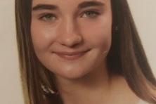 Portr&auml;t einer l&auml;chelnden jungen Frau mit langen, glatten Haaren und einem wei&szlig;en Oberteil auf hellem Hintergrund.