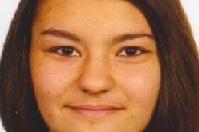 Portr&auml;t einer l&auml;chelnden jungen Frau mit langen, glatten Haaren und neutralem Hintergrund.