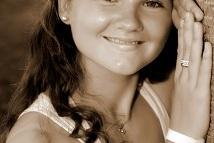 Portrait einer lächelnden jungen Frau, die mit beiden Händen an einem Baum lehnt, in sepiafarbenem Stil.