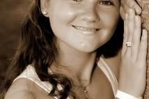 Portrait einer l&auml;chelnden jungen Frau, die mit beiden H&auml;nden an einem Baum lehnt, in sepiafarbenem Stil.