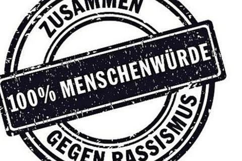 Stempel mit der Aufschrift &bdquo;Zusammen 100% Menschenw&uuml;rde gegen Rassismus&ldquo; auf wei&szlig;em Hintergrund.