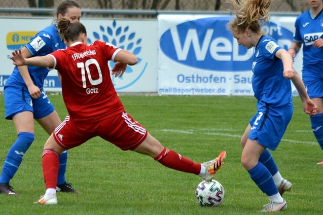 Zwei Fu&szlig;ballspielerinnen k&auml;mpfen um den Ball auf einem Rasenplatz, eine tr&auml;gt ein rotes Trikot mit der Nummer 10.