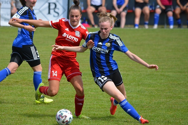 Zwei Fu&szlig;ballspielerinnen k&auml;mpfen um den Ball auf einem Rasenplatz w&auml;hrend eines Spiels.