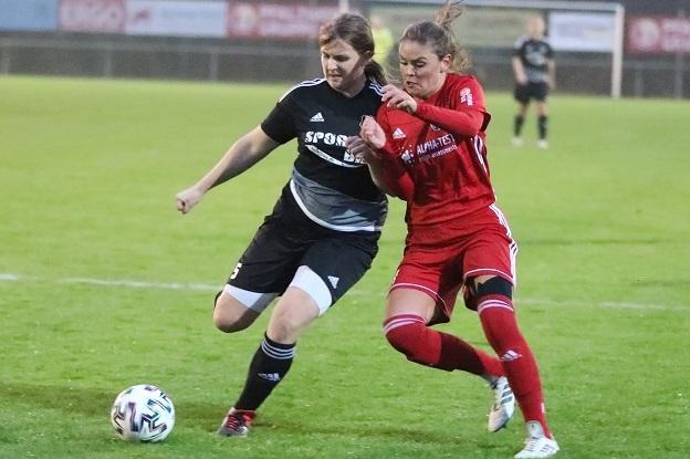 Zwei Fu&szlig;ballspielerinnen k&auml;mpfen um den Ball auf einem Rasenfeld w&auml;hrend eines Spiels.