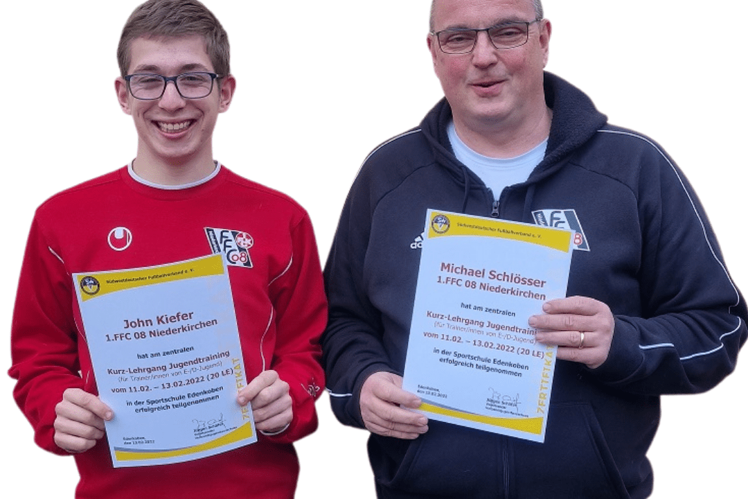 Zwei Männer halten jeweils ein Zertifikat in der Hand, stehen nebeneinander und lächeln freundlich in die Kamera.