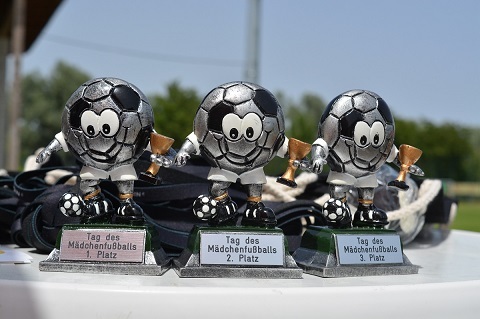 Drei Fu&szlig;ballpokale f&uuml;r Platzierungen bei einem M&auml;dchenspielfest stehen auf einem Tisch.