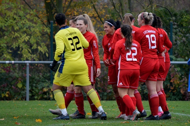 Gruppenbild von Fu&szlig;ballspielerinnen in roten Trikots, die mit einer Torh&uuml;terin in gelbem Trikot jubeln.