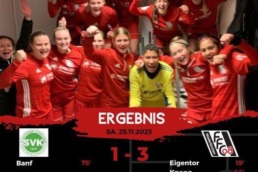 Gruppensiegfeier der Fu&szlig;ballmannschaft in rot, jubelnd mit einer Torwartspielerin in der Mitte, im Hintergrund ein Ergebnisbanner.