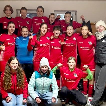 Gruppenbild von Jugendlichen in roten Fußballtrikots, die lächeln und posieren, umgeben von Umkleidekabine.