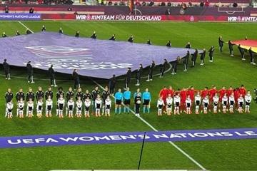 Zuschauer jubeln im Stadion, Spieler stehen auf dem Feld, Mädchengruppe mit Fahnen posiert für ein Foto.